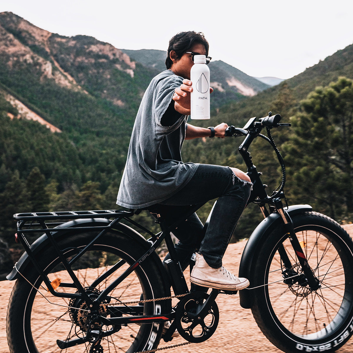 A rider carries a PATH water bottle on a mountain road